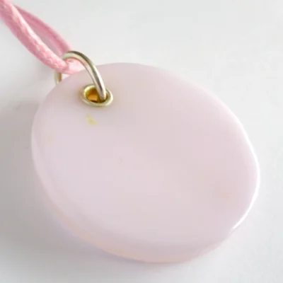 Back view of round pale pink dichroic glass pendant with sterling silver grommet