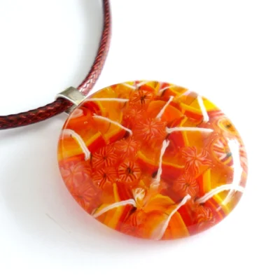 Orange yellow and white round fused glass pendant on a white background