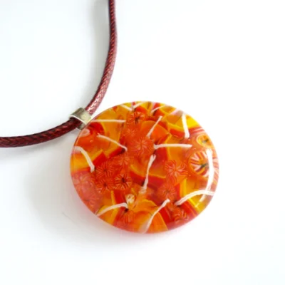Handmade fused glass pendant in patterns of orange, yellow leaves, 925 sterling silver bail attached and hangs from a cord necklace