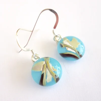 Handmade blue reactive glass earrings laying at an angle
