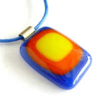 Handmade blue, red and yellow glass pendant hanging from a blue cord, showcasing a vibrant tack design. Pendant is a rectangle in shape and has rounded corners.
