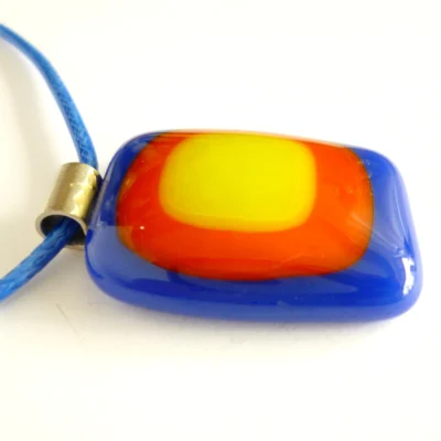A striking blue, red and yellow glass pendant suspended on a blue cord, highlighting the depth of glass