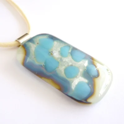 Cream silver and blue reactive glass pedant with outline to pattern caused by chemicals in the glass