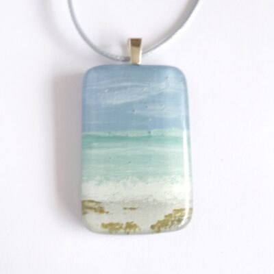 Hand-painted fused glass seascape pendant featuring mint sea and blue sky, hanging from a sterling silver bail.