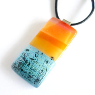 Orange and blue fused glass pendant with grasses decal on top and sterling silver bail