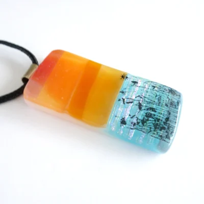 Side view of orange and blue fused glass pendant