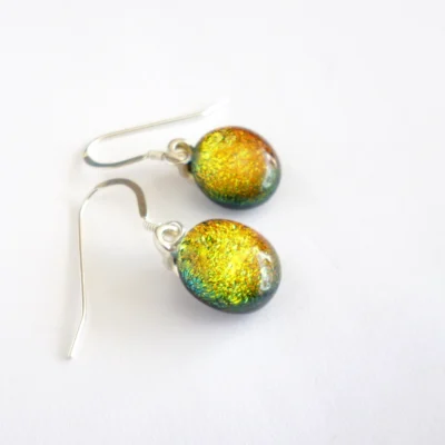 Dichroic glass earrings laying at an angle showing depth of glass