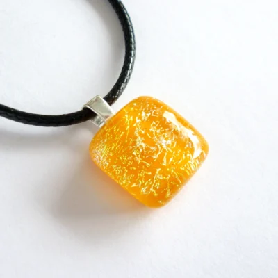 Fused dichroic glass pendant with orange base and clear dichroic on top