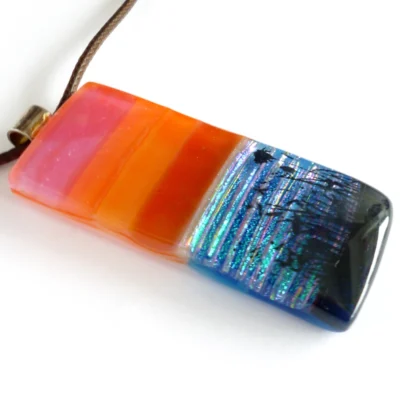 Side view of seascape fused glass pendant with sterling silver bail and cord