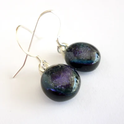 Side view of purple fused dichroic glass earrings showing depth of glass