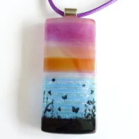 Front view of seascape pendant showing bands of different coloured glass and a dichroic glass for the sea. Black decal printed on top.