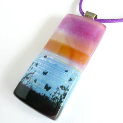 Pink purple seascape pendant laying at an angle on a white background.