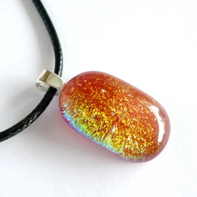 Close up of red dichroic glass pendant necklace with yellow green and red orange tones