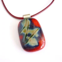 Red fused reactive glass pendant with pattern created from the reactive glass