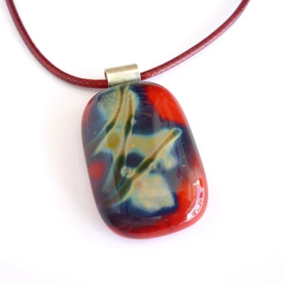 Red fused reactive glass pendant with pattern created from the reactive glass