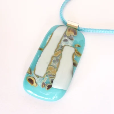 Turquoise and white reactive glass pendant necklace laying at an angle on a white background