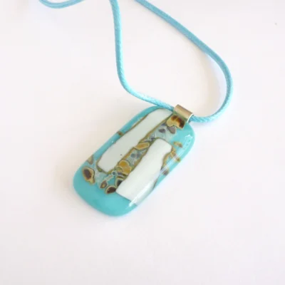 Turquoise & white reactive glass pendant with brown and silver pattern with 925 sterling silver bail and hangs from a blue cord necklace.