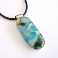 Vanilla and blue oblong glass pendant, sterling silver bail and black cord. Two shades of blue have been fused on top of vanilla, giving a chemical reaction.