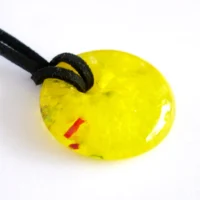 Handmade yellow donut fused glass pendant on a white background.