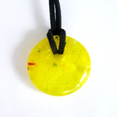 Front view of yellow fused glass pendant with hole in top and black cord threaded through.