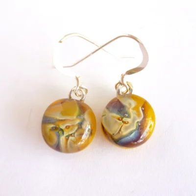 Yellow reactive glass earrings side by site. Earrings have a marble effect from the reaction in the glass