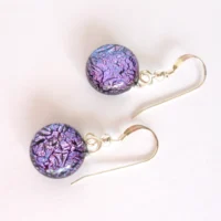 Pink crackle effect dichroic glass earrings hanging from silver plated bails and sterling silver ear wires.