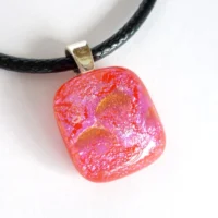 Small nearly square red dichroic glass pendant with colours of pink and orange on top. 925 sterling silver bail and black cord necklace.
