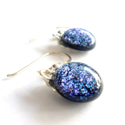 Angled view of dichroic glass earrings highlighting the domed effect and sterling silver ear wire shape.
