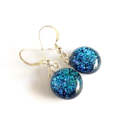 Blue dichroic glass earrings hanging from sterling silver ear wires.