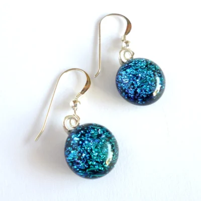 Smooth, rounded blue glass dichroic glass earrings cabochons showing the light reflecting off the polished surface.