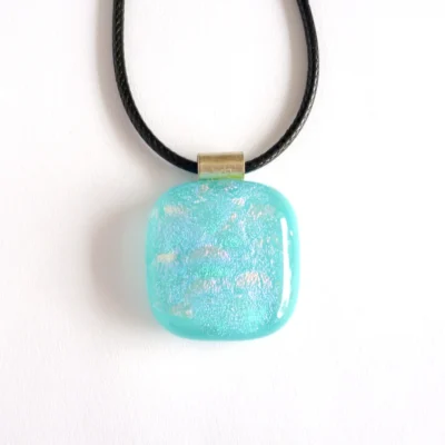 Front view of dichroic glass pendant, square in shape and hanging from a black cord necklace.
