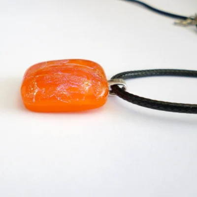 Side view of orange dichroic glass pendant showing depth and layers of glass.