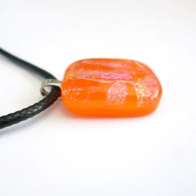 Side view of orange dichroic glass pendant showing smooth and glossy finish.