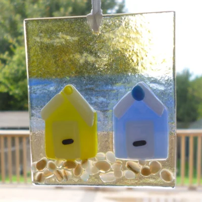 Fused glass coastal suncatcher in yellow and blue, hanging from a white ribbon.