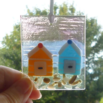 Fused glass coastal suncatcher being held in the light.