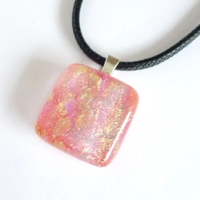 Different angle of pink pendant laying on a white background.