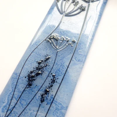 Close up of black stringer detail on blue fused glass dandelion suncatcher.