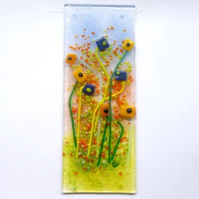 Handcrafted blue and orange flower hanging from a clear cord. Quirky orange and dark blue square flowers with long green stems. Orange, red and green frit for decoration.