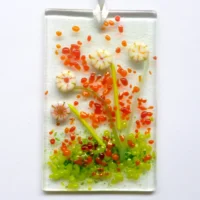 Small rectangle cream glass flower suncatcher with quirky cream flowers made with discs of glass. Orange and green frit for decoration.