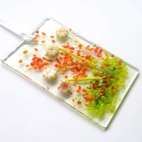 Cream glass flower suncatcher at an angle showing depth of glass flowers. Hangs from a white ribbon.