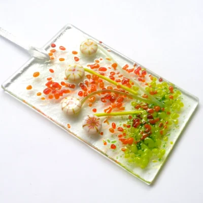 Cream glass flower suncatcher at an angle showing depth of glass flowers. Hangs from a white ribbon.