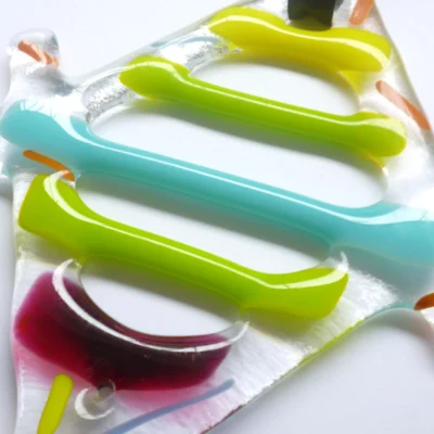 Close up of coloured strips of glass in yellow, green, red and turquoise, showing depth.