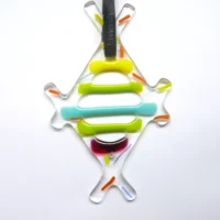 Diamond shaped abstract fused glass suncatcher. Outline of clear glass with strips of yellow, green, red and turquoise glass going across the diamond shape. Hanging from a black Livicraft ribbon.