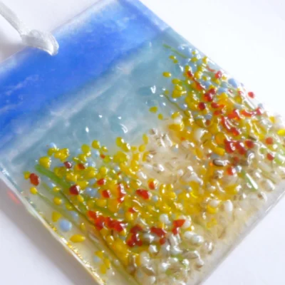 Fused glass coastal suncatcher laying at an angle, close up view showing detail of glass.