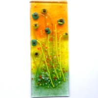 Fused glass floral suncatcher featuring quirky green square flowers on long stems with orange and green frit.