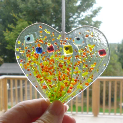 Fused glass heart suncatcher being held at the bottom to show the size