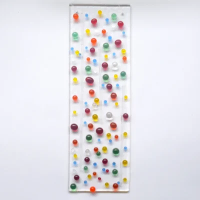 Fused glass suncatcher with multi-colour beads and clear stringers fused on top of a clear piece of glass. Hole at the top with a clear wire threaded through to hang from.