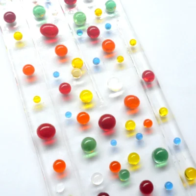 Close up of multi-colour fused glass suncatcher with colourful glass beads, yellow, orange, green, red and blue.