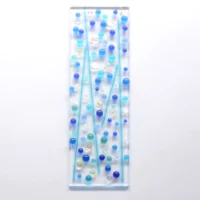 Fused glass suncatcher with blue glass beads fused on top. Clear glass with blue, turquoise and dichroic glass beads and stringers fused on top of a clear piece of glass.