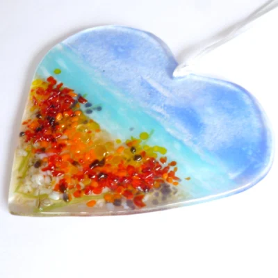 Fused glass heart suncatcher laying at an angle showing detail of glass.